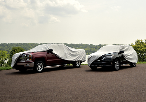 suv and truck with car cover partially covering them